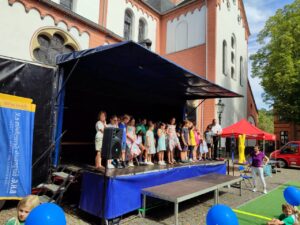 Straßenfest der Bürgerhilfe Gerresheim (B.H.G.). Auftritt der SingPause-Kinder aus der Schule Unter den Eichen mit den Klassen 3 A, 3 B, 3 C, 3 D mit ihrer Singleiterin Natalia Hildebrandt